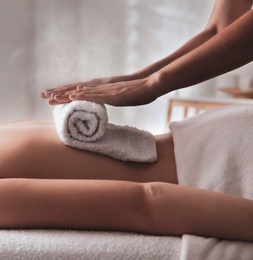 Image of Young woman receiving hot towel massage in spa salon, closeup