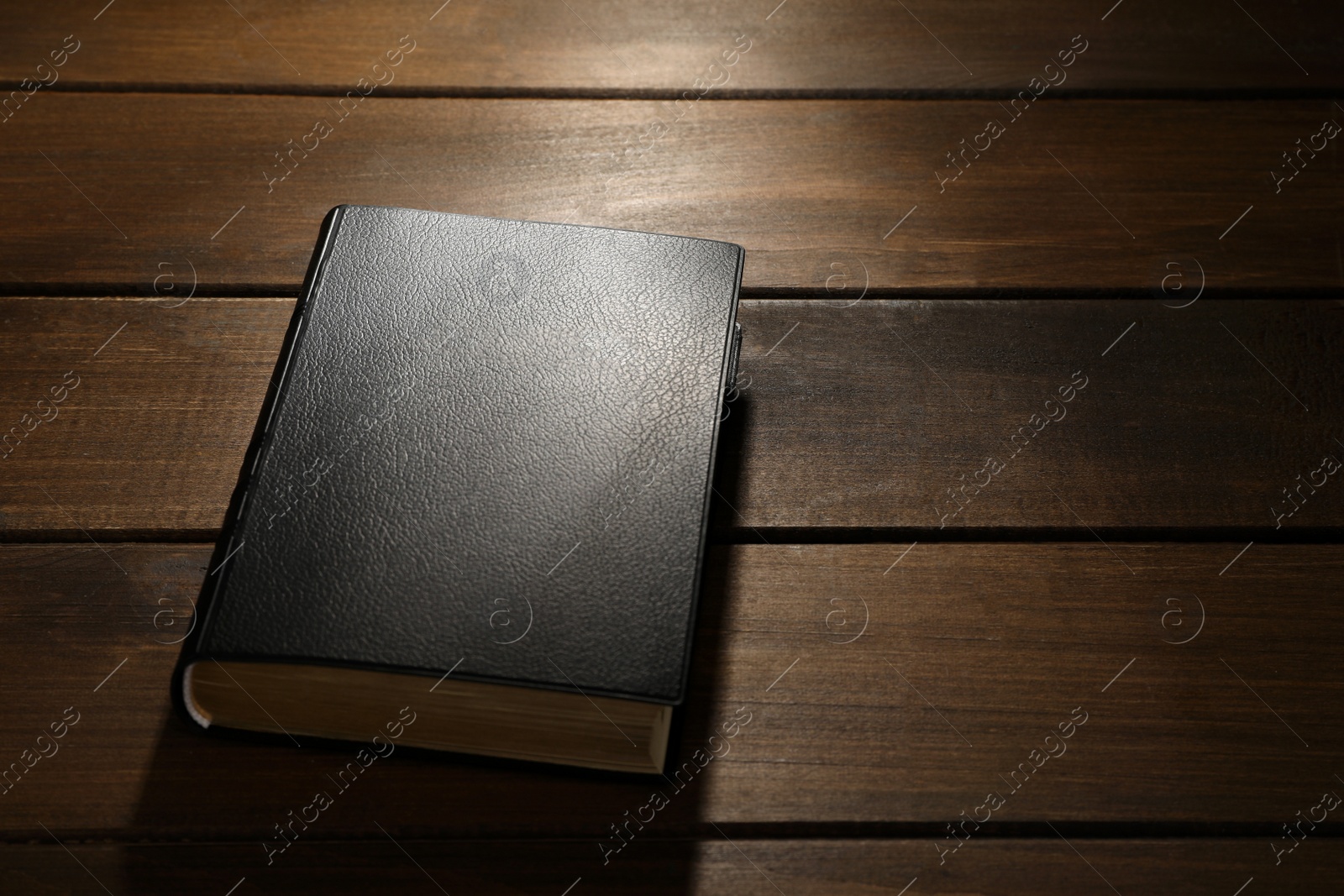 Photo of Bible on wooden table, space for text. Christian religious book