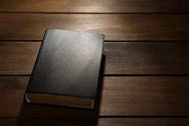 Bible on wooden table, space for text. Christian religious book