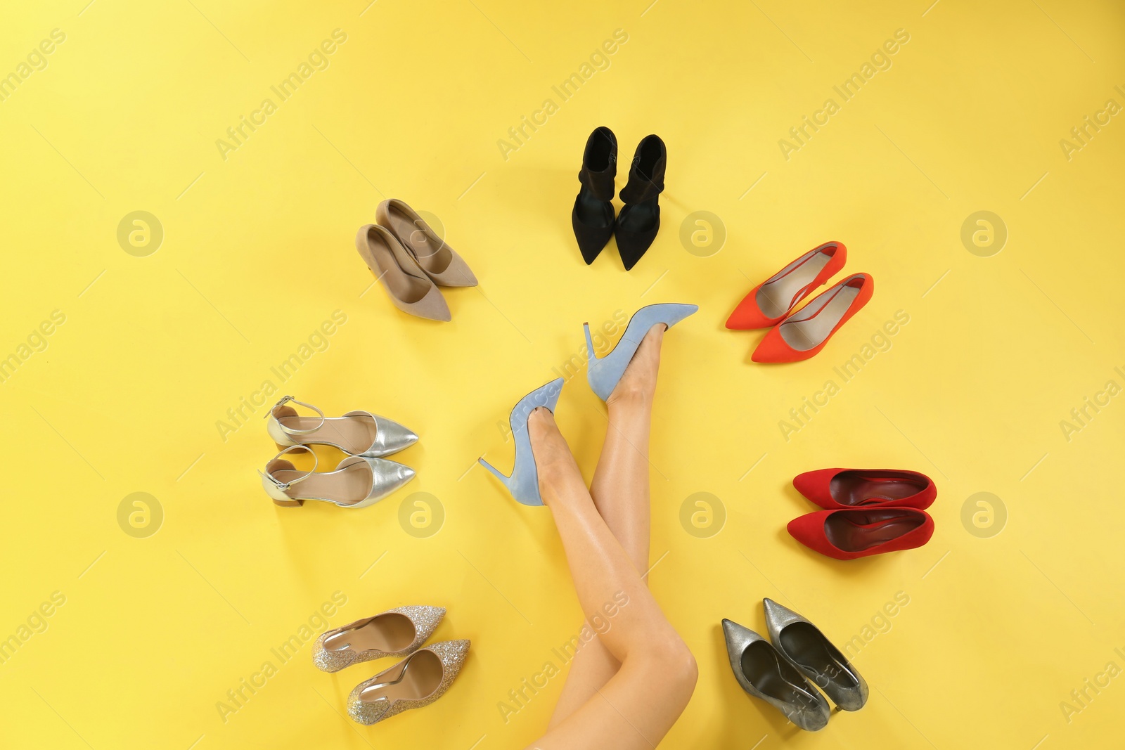 Photo of Woman and different high heel shoes on yellow background, top view