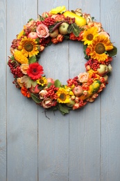 Photo of Beautiful autumnal wreath with flowers, berries and fruits on light grey wooden background, top view. Space for text