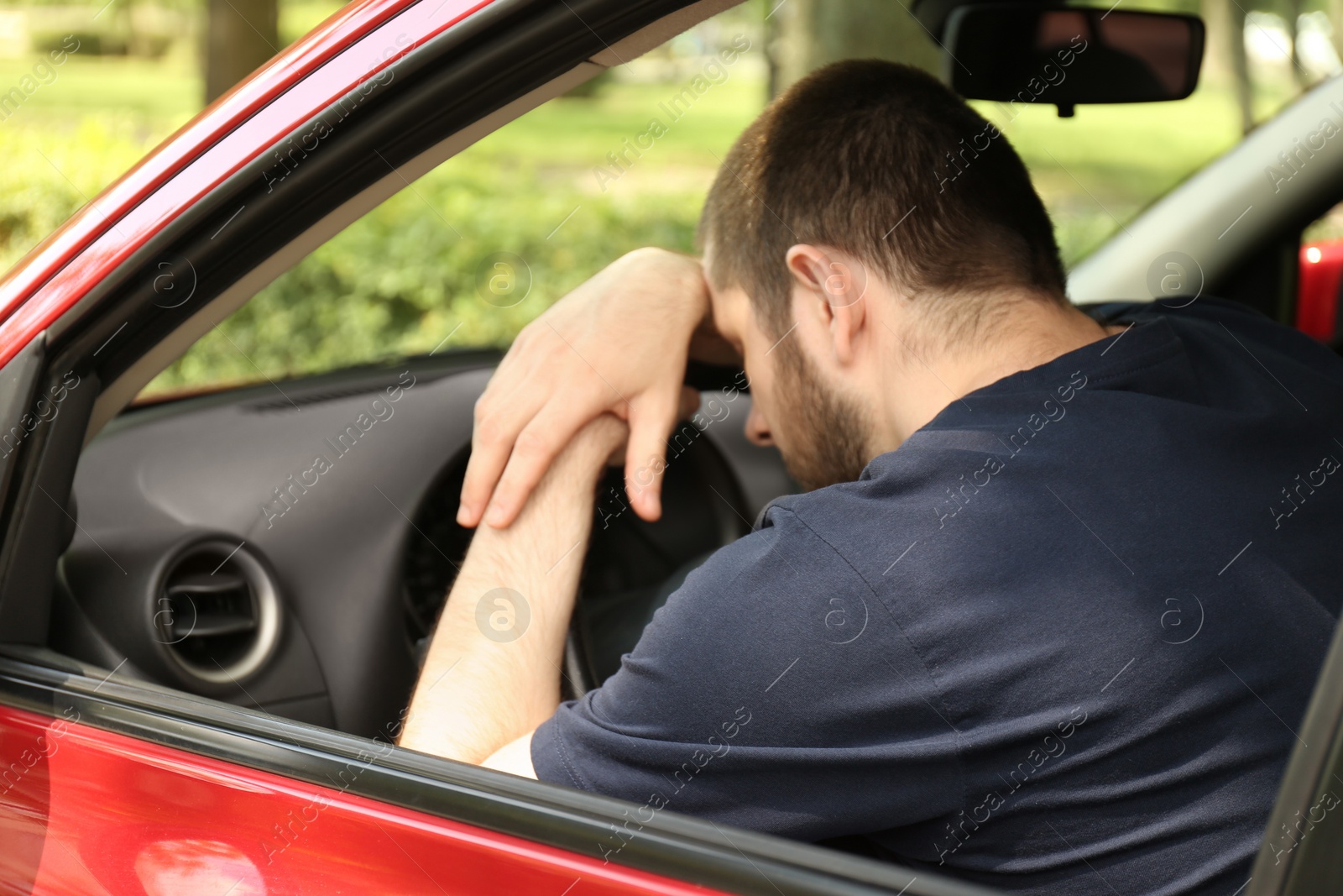 Photo of Tired man sleeping on steering wheel in his car