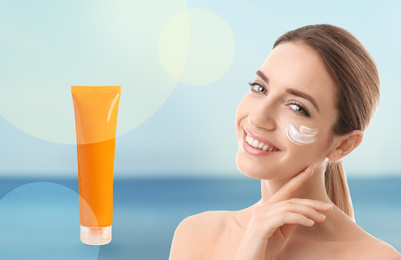 Young woman and tube with sun protection cream on blurred background