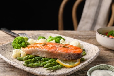 Photo of Healthy meal. Tasty grilled salmon with vegetables served on wooden table, closeup