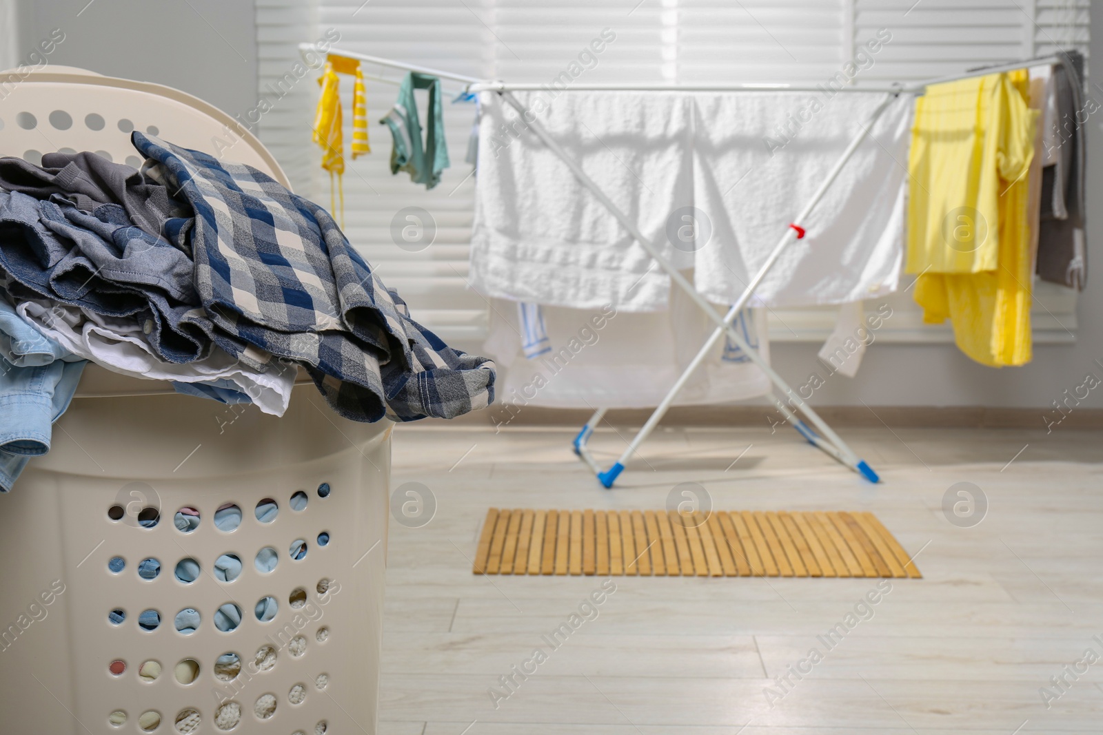 Photo of Plastic laundry basket overfilled with clothes in bathroom, closeup. Space for text