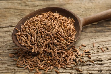 Spoon with caraway seeds on wooden table, closeup