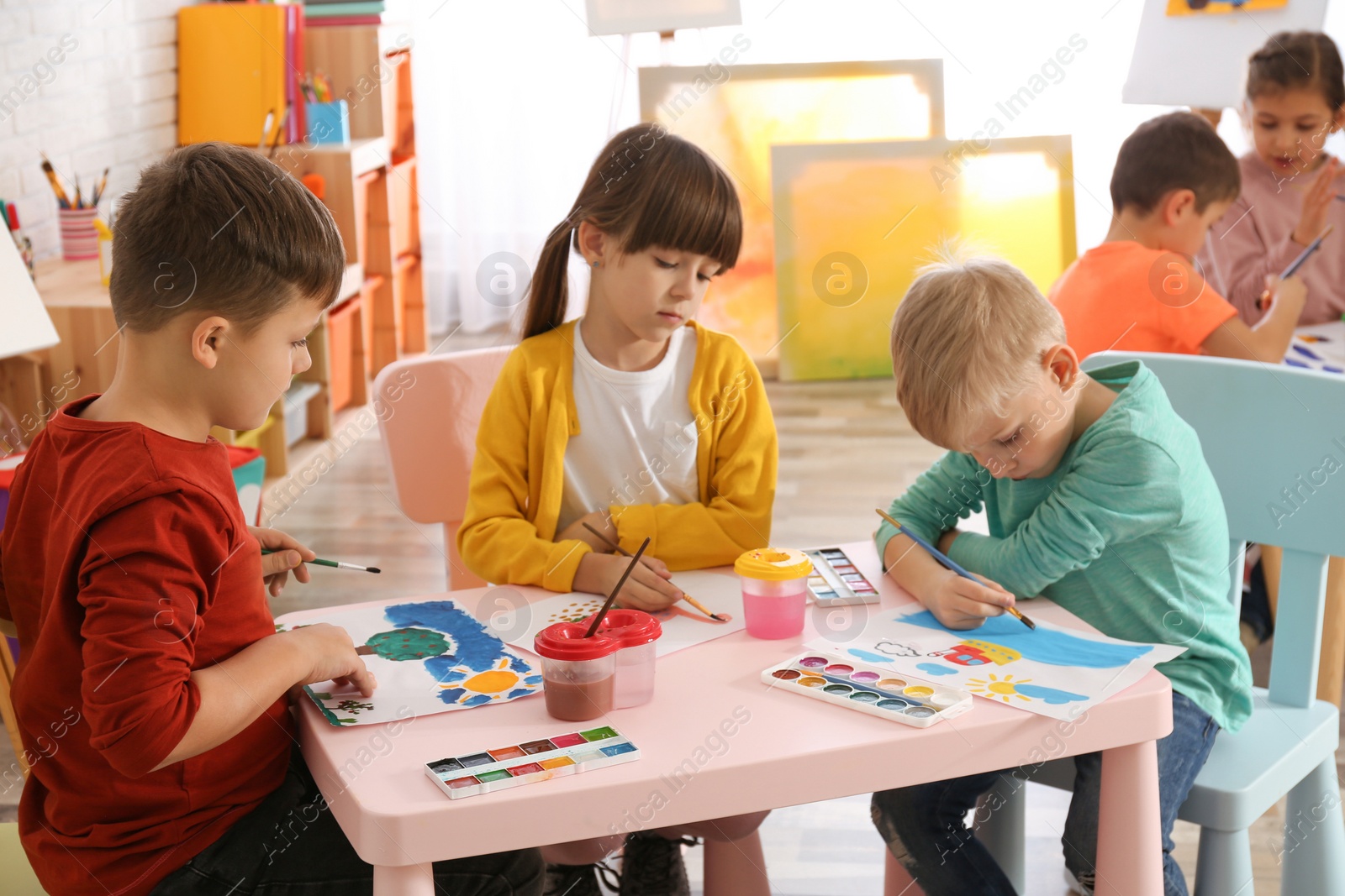 Photo of Cute little children painting at table in room