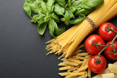 Different types of pasta, spices and products on black background, flat lay. Space for text