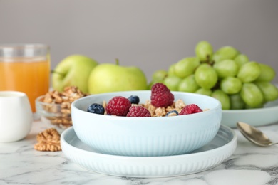 Photo of Healthy breakfast with granola and berries served on white marble table