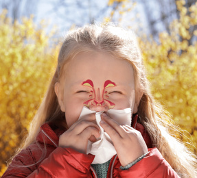 Little girl suffering from runny nose as allergy symptom outdoors. Sinuses illustration on face