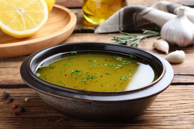 Bowl with lemon sauce on wooden table, closeup. Delicious salad dressing