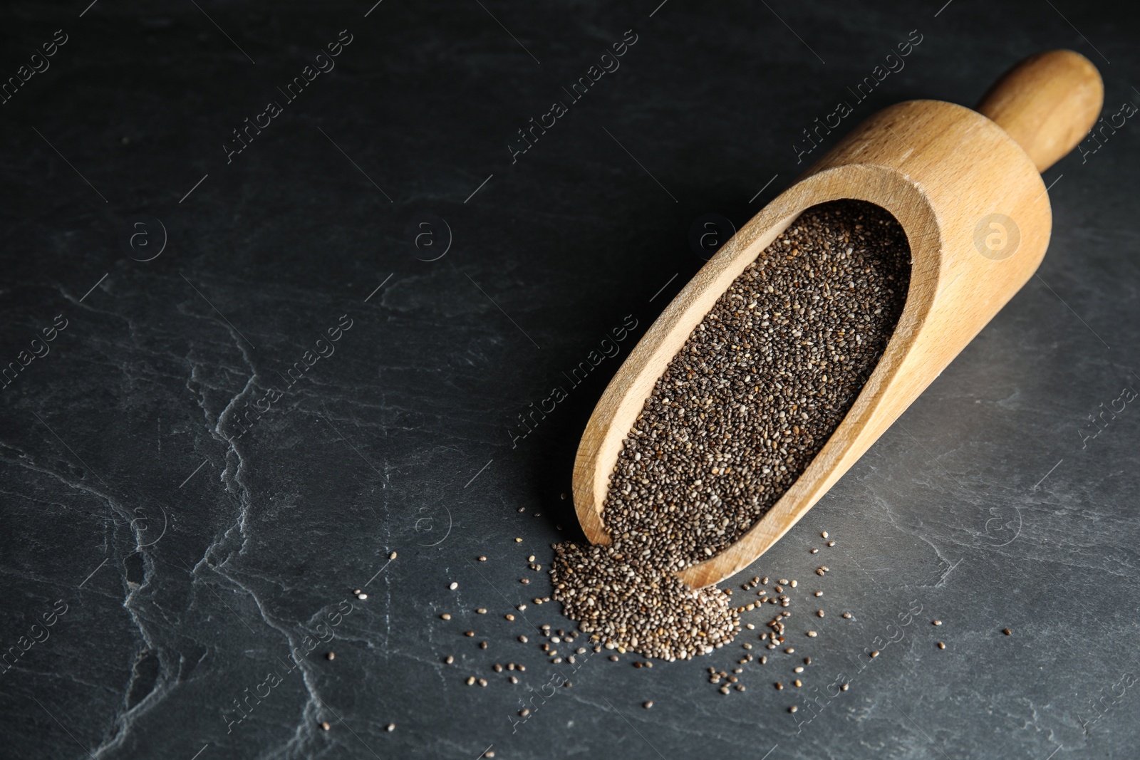 Photo of Scoop and scattered chia seeds on grey table, space for text