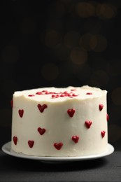 Photo of Bento cake with red cream hearts on black table, closeup. St. Valentine's day surprise