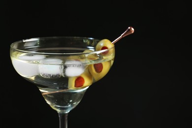 Photo of Martini cocktail with ice and olives on dark background, closeup. Space for text