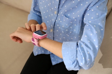 Photo of Girl using stylish smart watch on sofa, closeup