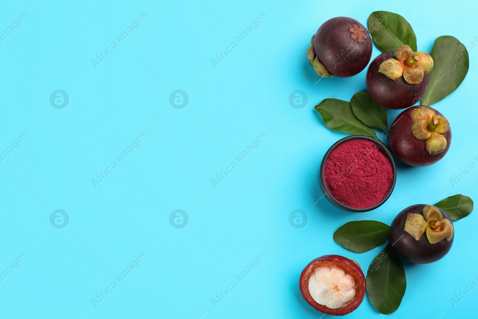 Photo of Purple mangosteen powder and fruits on light blue background, flat lay. Space for text
