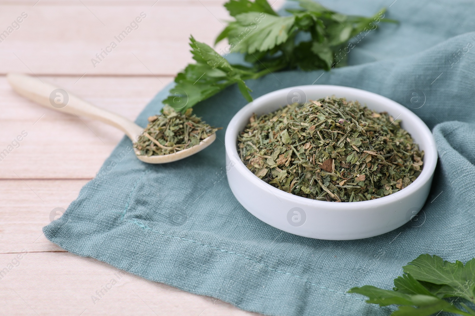 Photo of Dried aromatic parsley and fresh leaves on white wooden table, space for text