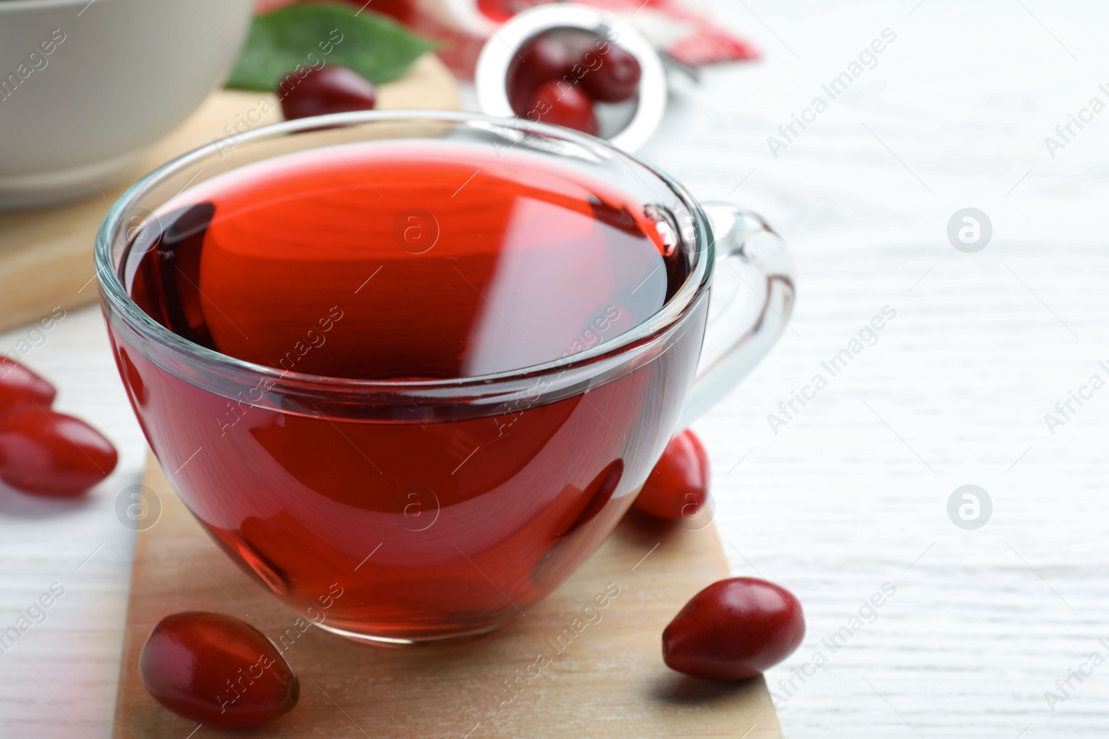 Photo of Glass cup of fresh dogwood tea and berries on white wooden table. Space for text