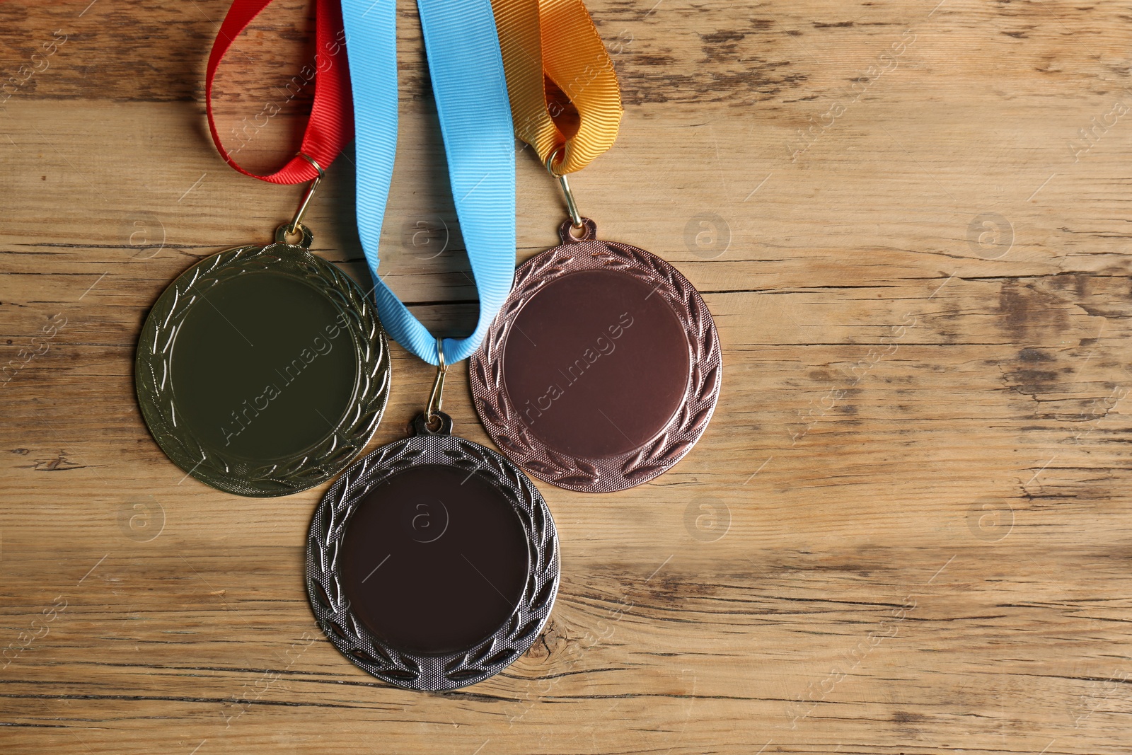 Photo of Gold, silver and bronze medals on wooden background, flat lay. Space for design