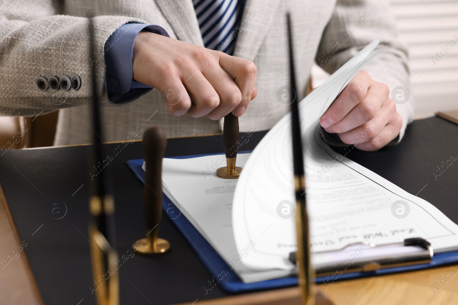 Photo of Notary stamping document at table in office, closeup