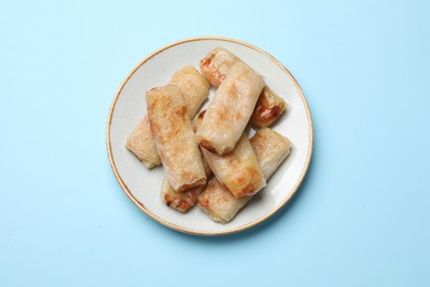 Photo of Fried spring rolls on light blue table, top view