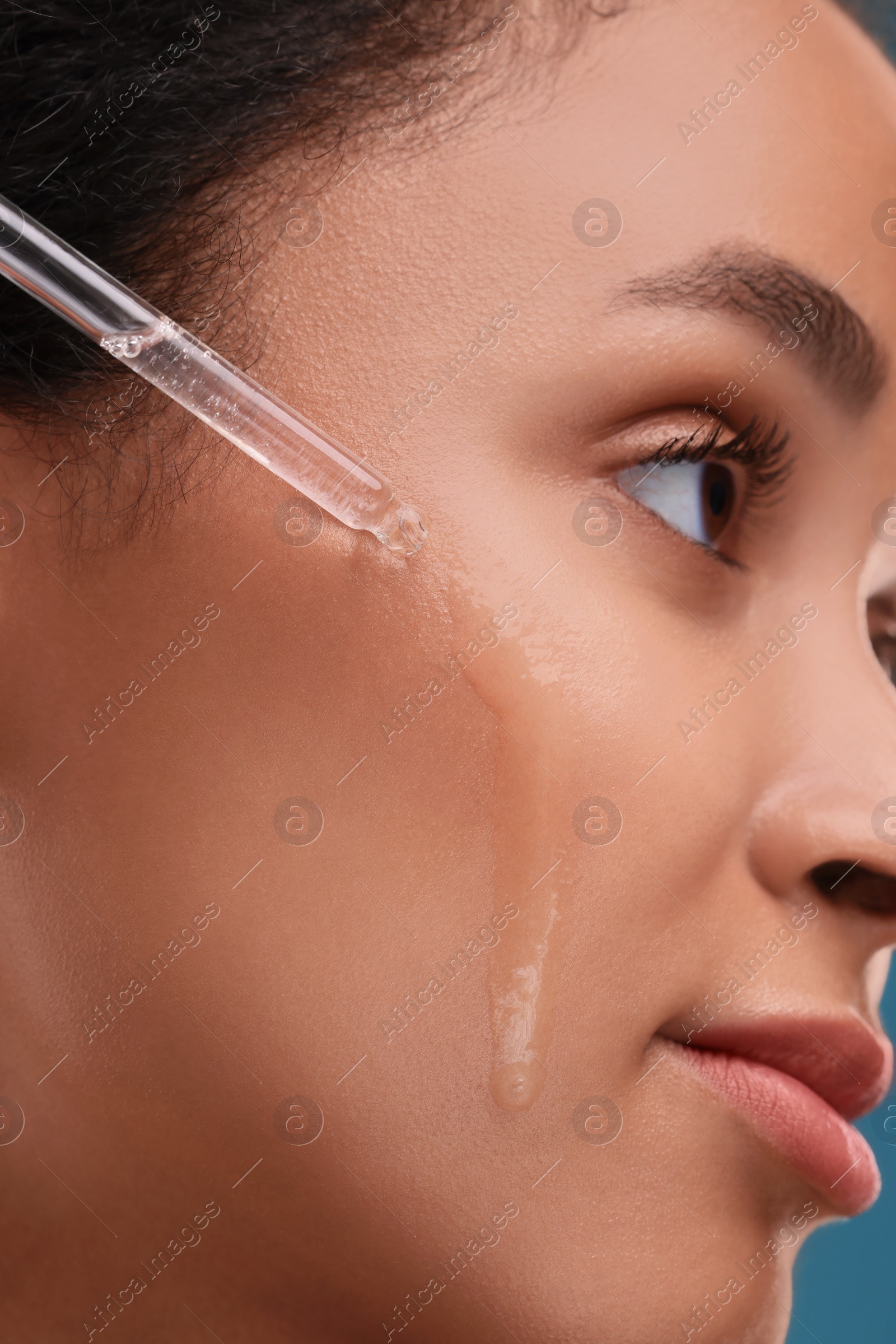 Photo of Beautiful woman applying serum onto her face, closeup