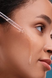 Beautiful woman applying serum onto her face, closeup