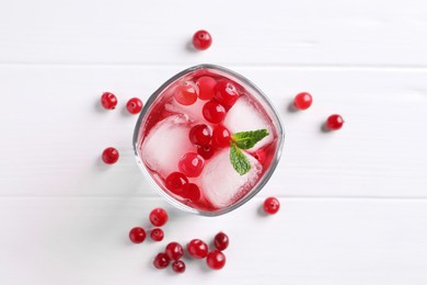 Photo of Tasty cranberry juice with ice cubes in glass and fresh berries on white wooden table, flat lay