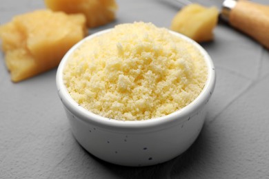 Photo of Delicious grated parmesan cheese in bowl on gray background, closeup