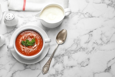 Dish with fresh homemade tomato soup and space for text on marble table, top view