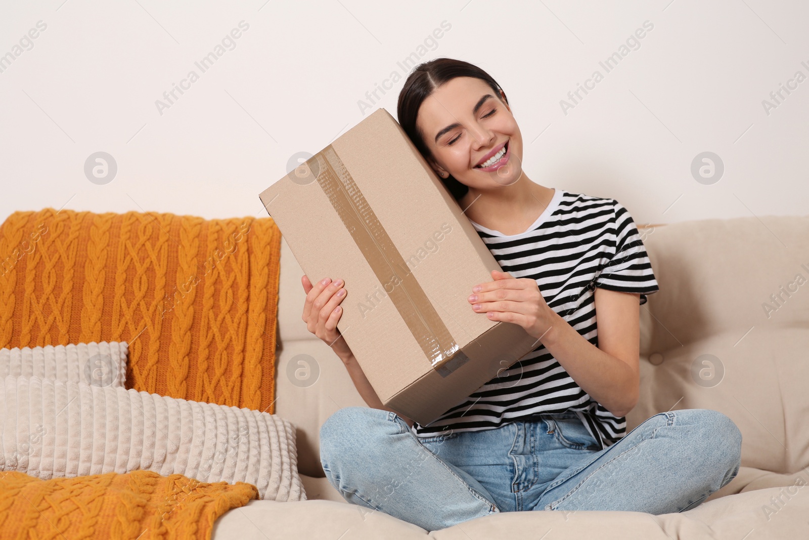 Photo of Happy young woman with parcel on sofa at home. Internet shopping