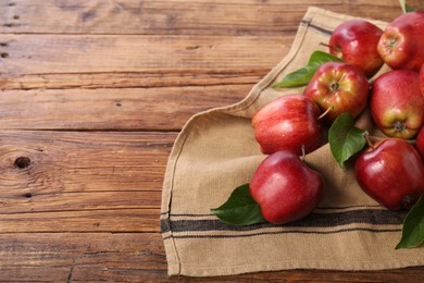 Photo of Ripe red apples with leaves on wooden table. Space for text