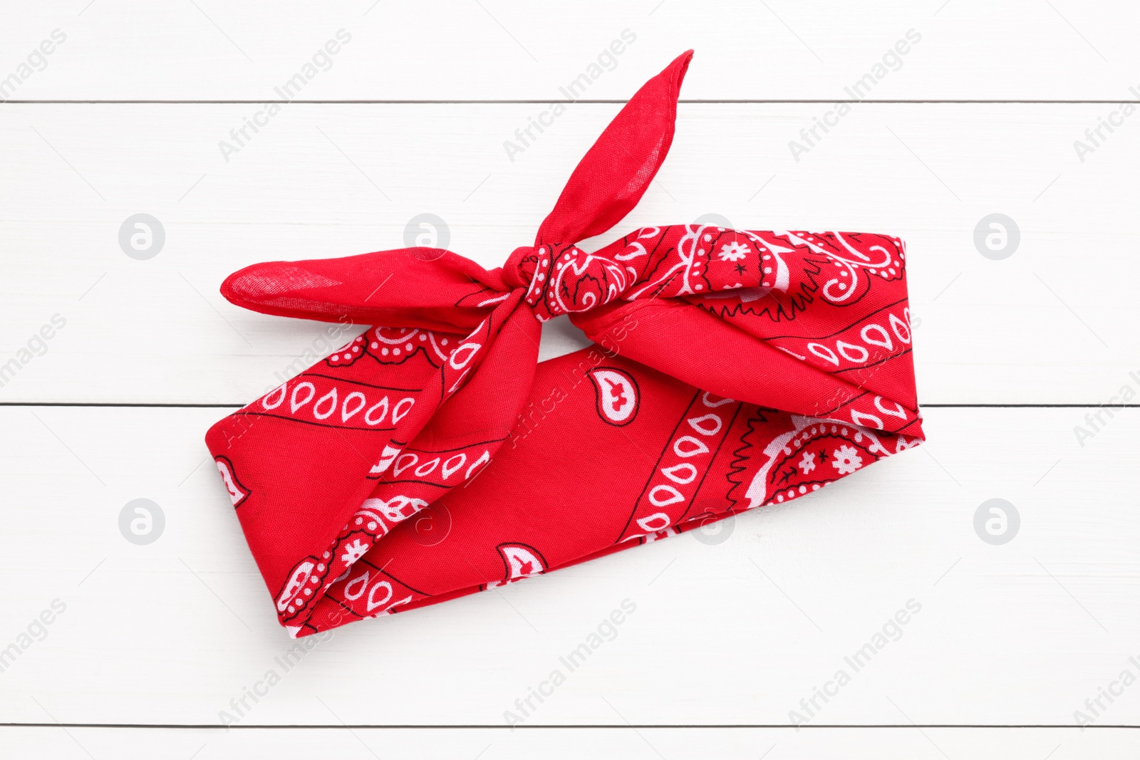 Photo of Tied red bandana with paisley pattern on white wooden table, top view