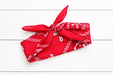 Photo of Tied red bandana with paisley pattern on white wooden table, top view