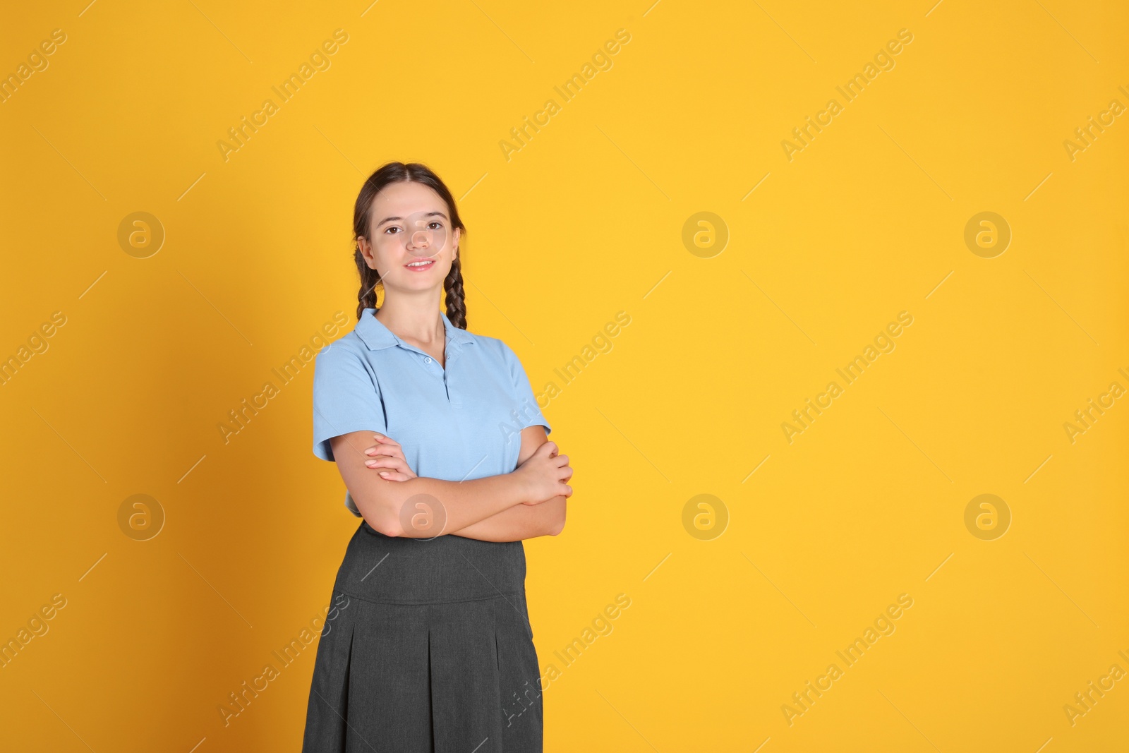 Photo of Teenage girl wearing school uniform on orange background, space for text