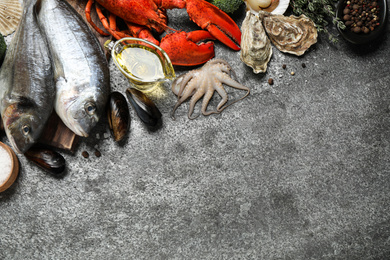 Fresh fish and different seafood on grey table, flat lay. Space for text