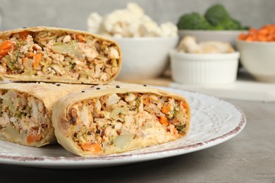Photo of Pieces of delicious strudel with chicken and vegetables on light grey textured table, closeup