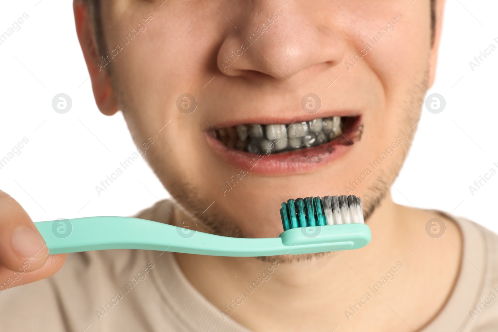 Photo of Man brushing teeth with charcoal toothpaste on white background, closeup