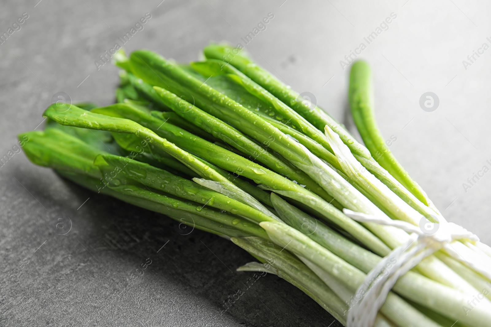 Photo of Bunch of wild garlic or ramson on grey table, closeup