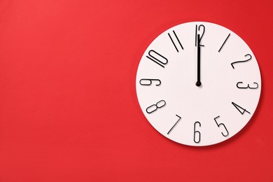 Modern clock on red background, top view. Space for text