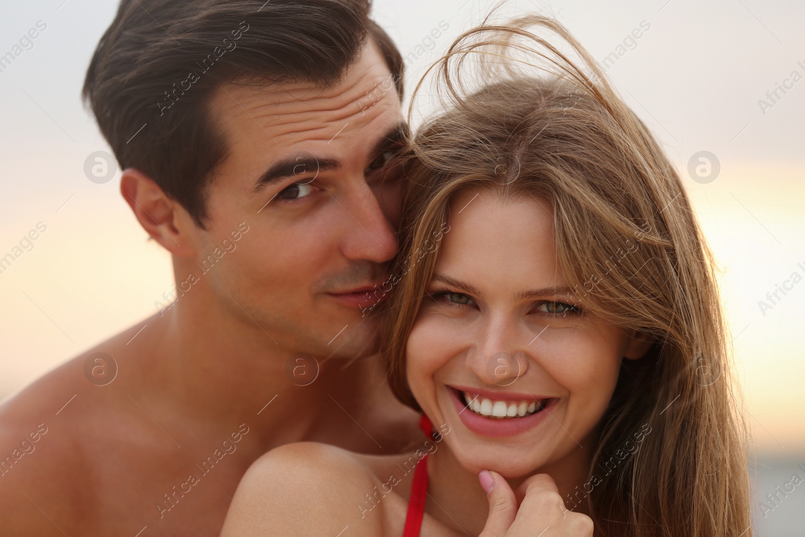 Photo of Happy young couple spending time together on sea beach at sunset