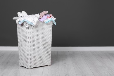 Laundry basket with baby clothes, shoes and crochet toy indoors, space for text