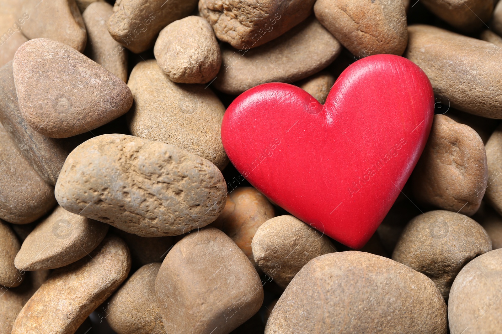 Photo of Red decorative heart on stones, top view