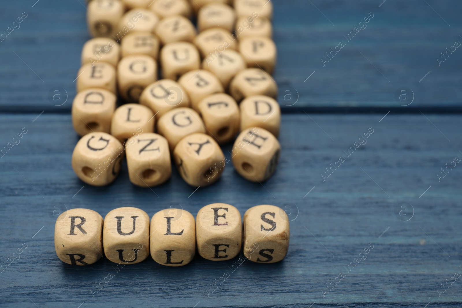 Photo of Word Rules made of cubes with letters on blue wooden table