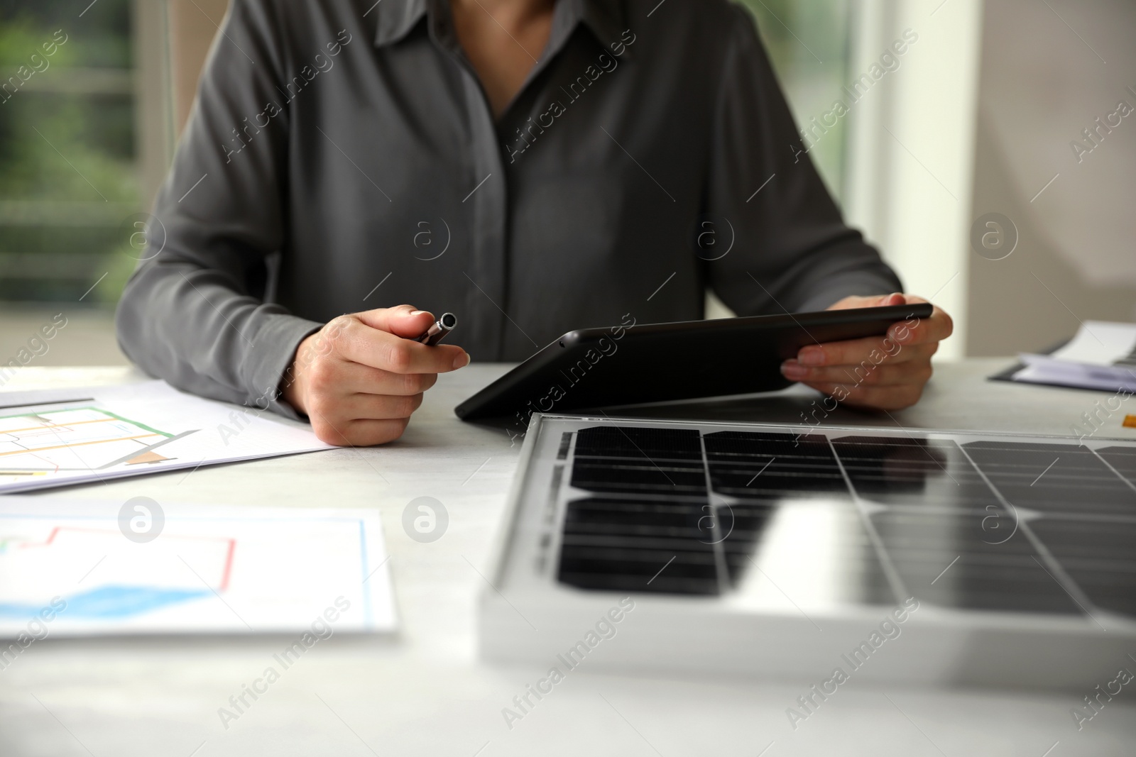 Photo of Woman working on project with solar panels at table in office, closeup
