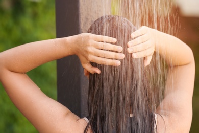 Woman washing hair in outdoor shower on summer day, closeup