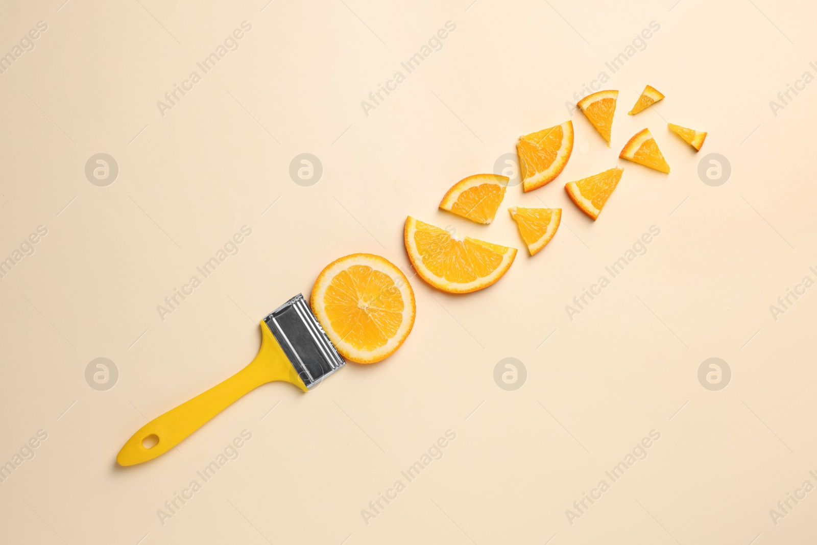 Photo of Creative flat lay composition with paint brush and slices of orange on beige background