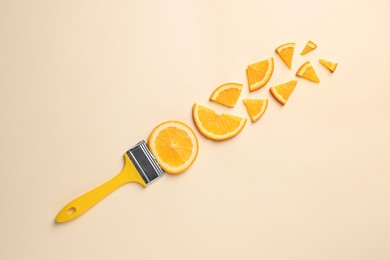 Photo of Creative flat lay composition with paint brush and slices of orange on beige background