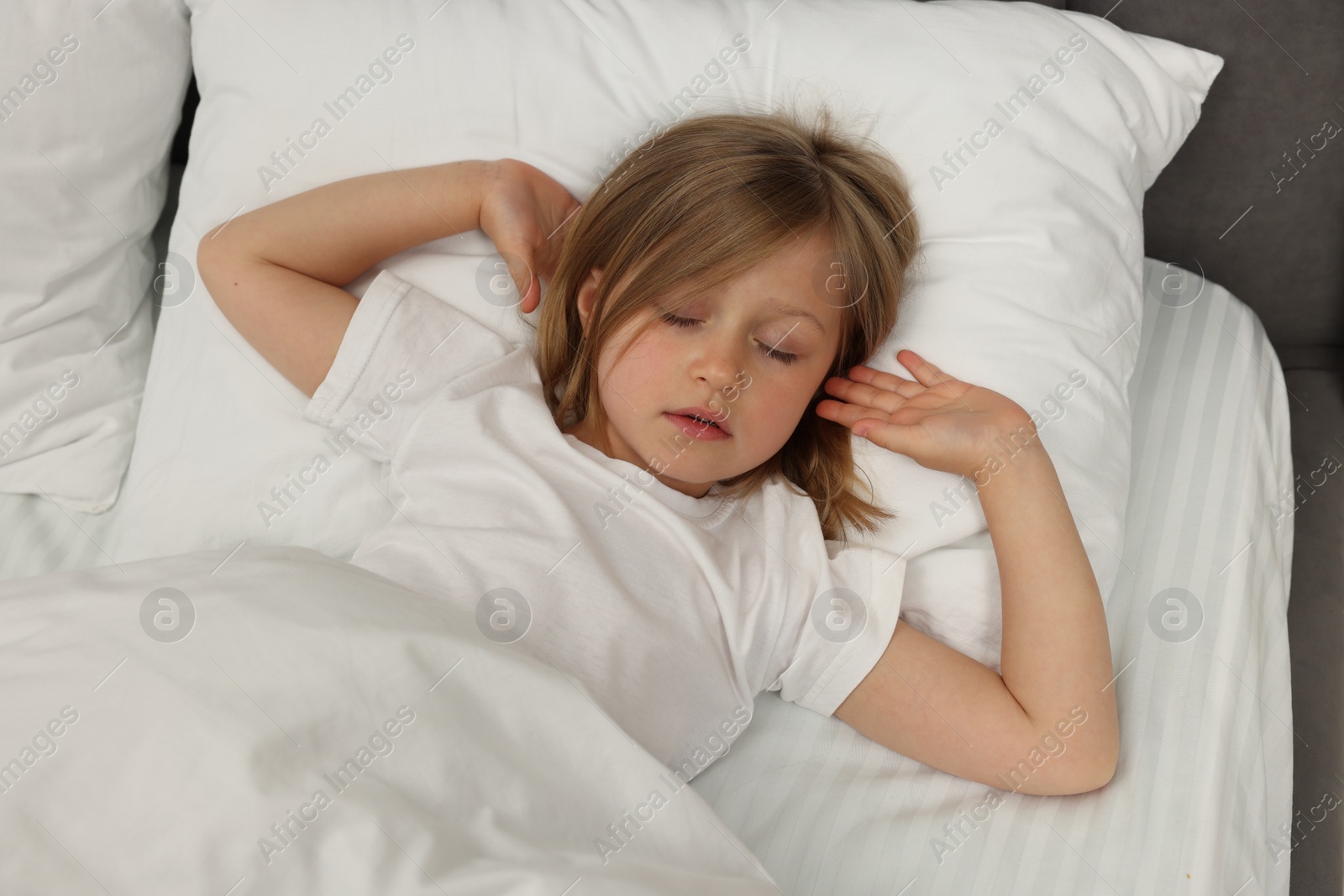 Photo of Little girl snoring while sleeping in bed, above view