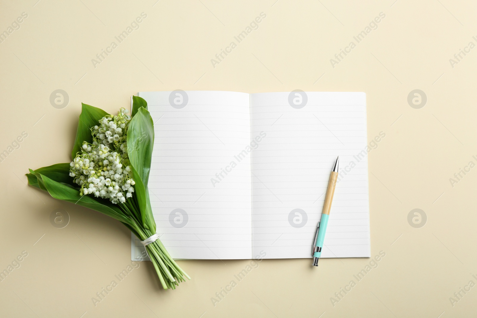 Photo of Notebook, pen and lily of the valley bouquet on color background, flat lay. Space for text